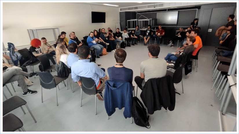 Foto del Open Space de comunidades en la que se ve a una treintena de asistentes sentados en círculo.